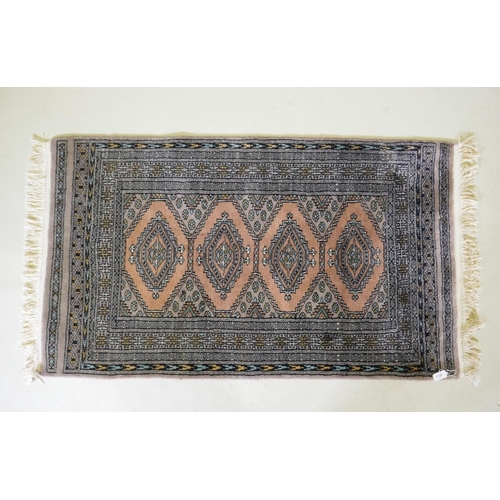 1138 - A hand woven wool rug with geometric design on a faded brown field, 79 x 136cm