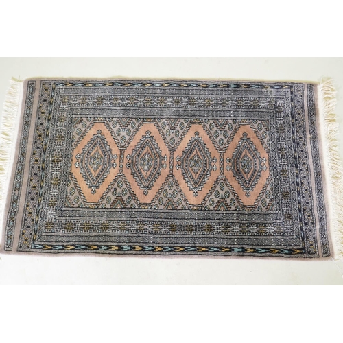 1138 - A hand woven wool rug with geometric design on a faded brown field, 79 x 136cm