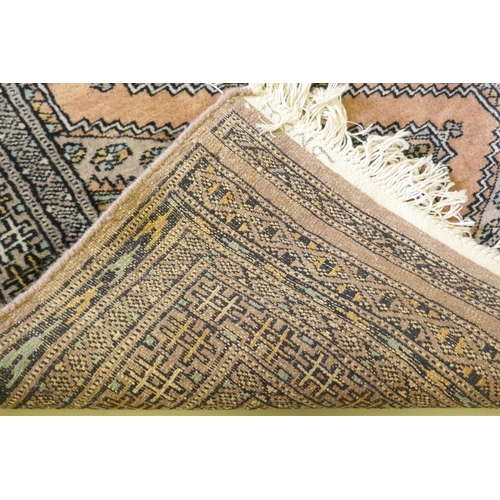 1138 - A hand woven wool rug with geometric design on a faded brown field, 79 x 136cm