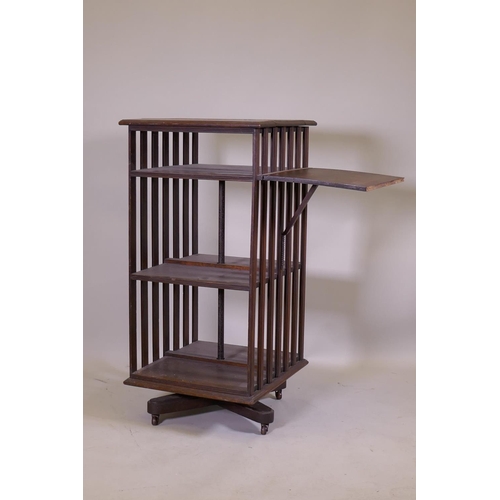 1158 - A Victorian oak revolving bookcase, three tiered with a ratcheted drop flap, raised on an iron base,... 