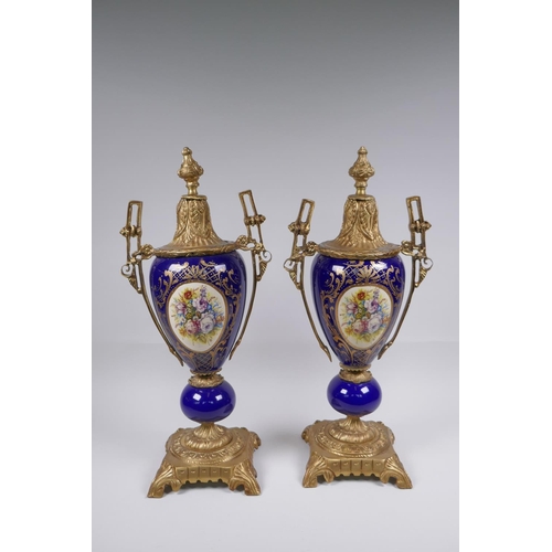 134 - A pair of ormolu and Sevres style porcelain urns with two handles and decorative panels depicting a ... 