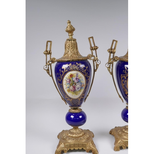 134 - A pair of ormolu and Sevres style porcelain urns with two handles and decorative panels depicting a ... 