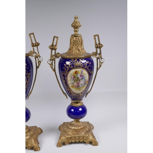 134 - A pair of ormolu and Sevres style porcelain urns with two handles and decorative panels depicting a ... 