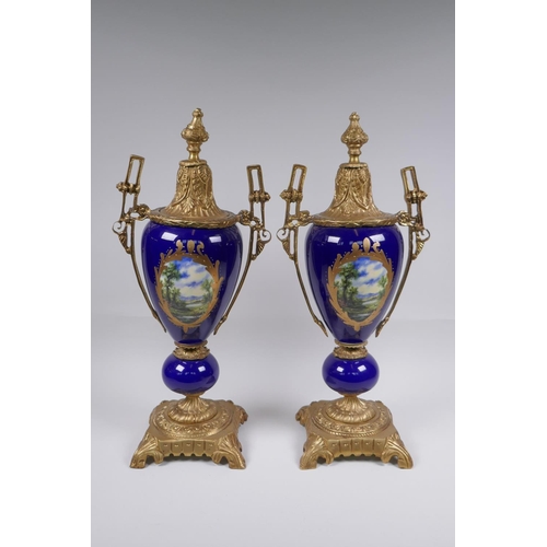 134 - A pair of ormolu and Sevres style porcelain urns with two handles and decorative panels depicting a ... 