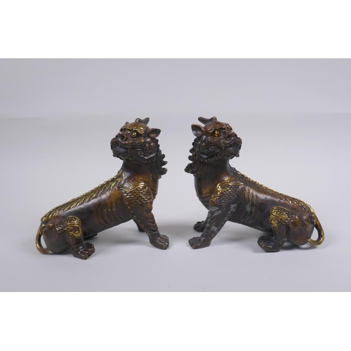 150 - A pair of Chinese filled bronze kylin with gilt highlights, impressed seal mark to base, 14cm long, ... 