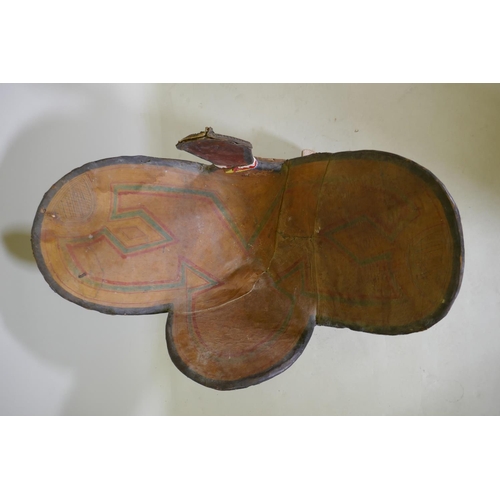 154 - A hand painted animal hide, wood and leather camel saddle with metal mounts and stand, probably of t... 