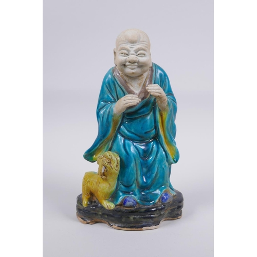 158 - A Chinese polychrome porcelain figure of Lohan with a fo dg, AF, 21cm high