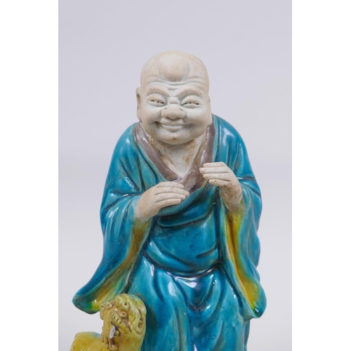 158 - A Chinese polychrome porcelain figure of Lohan with a fo dg, AF, 21cm high