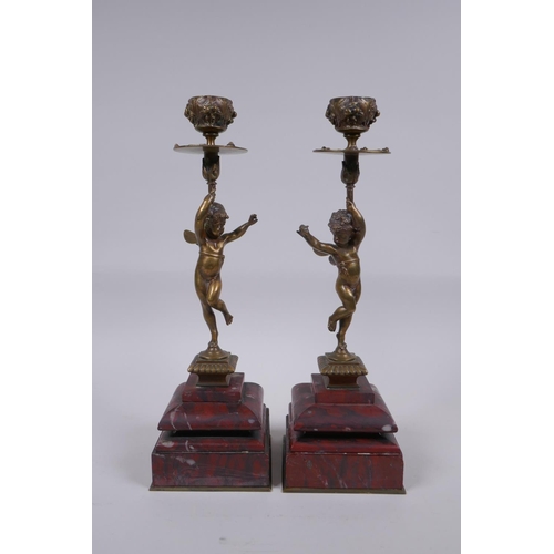 17 - A pair of Victorian bronze candlesticks in the form of a winged putti, on red marble bases, 28cm hig... 