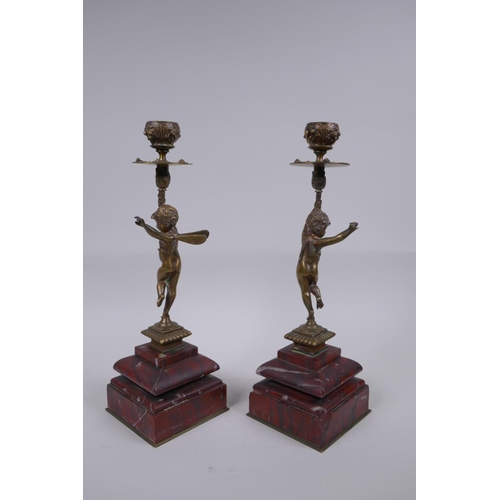 17 - A pair of Victorian bronze candlesticks in the form of a winged putti, on red marble bases, 28cm hig... 