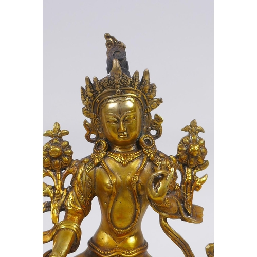 210 - A Tibetan gilt bronze figure of a female deity seated on a lotus flower, impressed double vajra mark... 