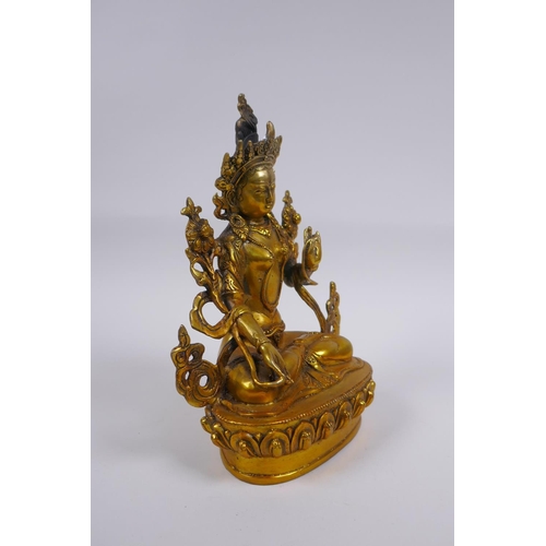 210 - A Tibetan gilt bronze figure of a female deity seated on a lotus flower, impressed double vajra mark... 