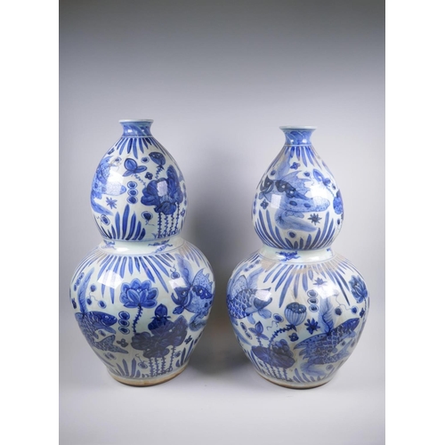 56 - A near pair of Chinese blue and white porcelain double gourd vases decorated with carp in a lotus po... 