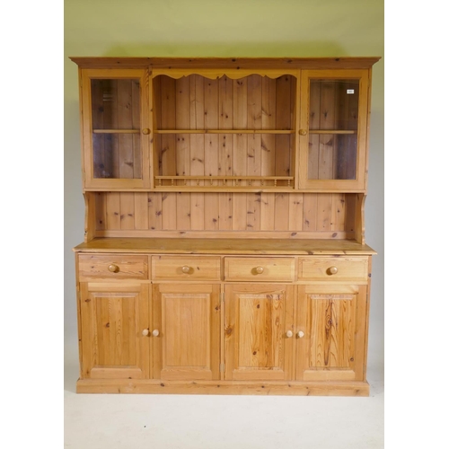 1131 - A pine dresser, the upper section with two glazed door flanking open shelves, the base with four dra... 