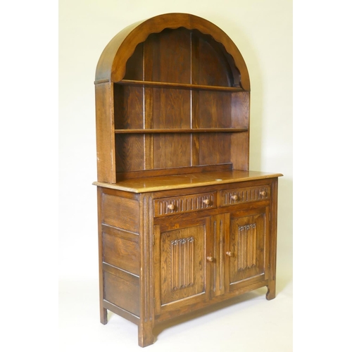 1014 - A mid century oak dresser with dome shaped upper rack on a base of two drawers over two cupboards, 1... 