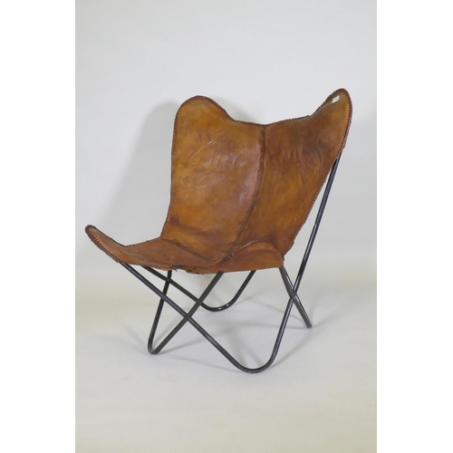 1015 - A leather butterfly chair with tooled elephant decoration, on a tubular metal frame