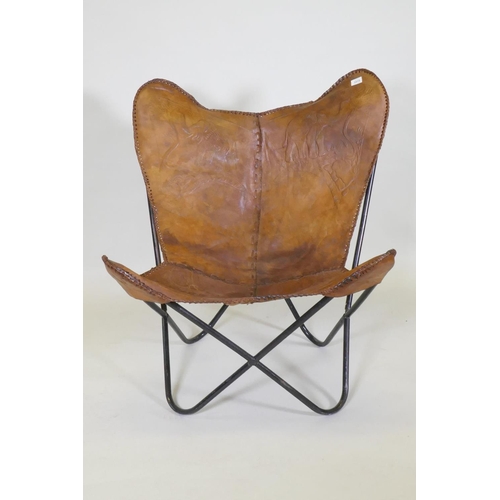 1015 - A leather butterfly chair with tooled elephant decoration, on a tubular metal frame