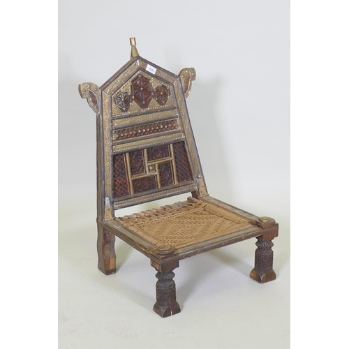 1030 - An antique Indian Pidha low chair with folding back, brass and iron mounts and webbed seat