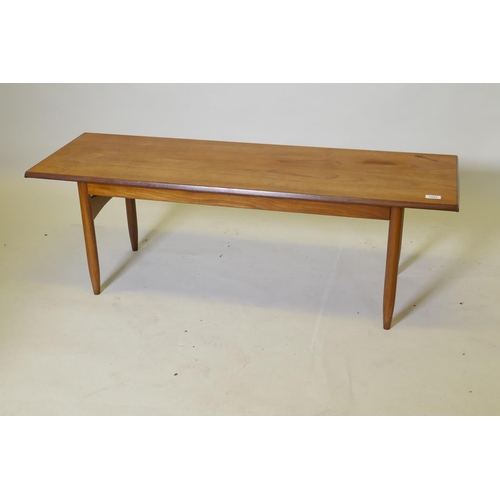 1042 - A mid century teak coffee table, raised on tapering supports united by shaped end stretchers, 40 x 1... 