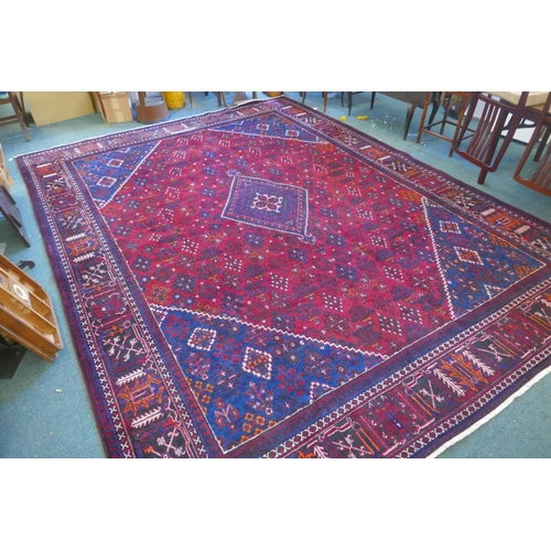 1060 - A claret and blue ground Persian Joshaghan tribal carpet with traditional medallion design, signed, ... 