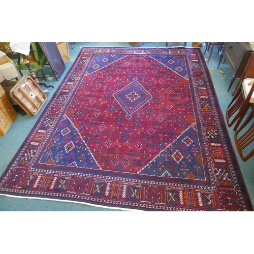 1060 - A claret and blue ground Persian Joshaghan tribal carpet with traditional medallion design, signed, ... 