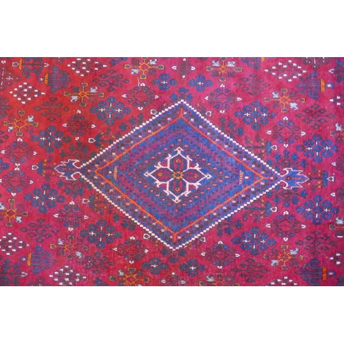 1060 - A claret and blue ground Persian Joshaghan tribal carpet with traditional medallion design, signed, ... 