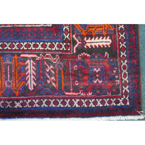 1060 - A claret and blue ground Persian Joshaghan tribal carpet with traditional medallion design, signed, ... 