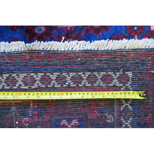 1060 - A claret and blue ground Persian Joshaghan tribal carpet with traditional medallion design, signed, ... 