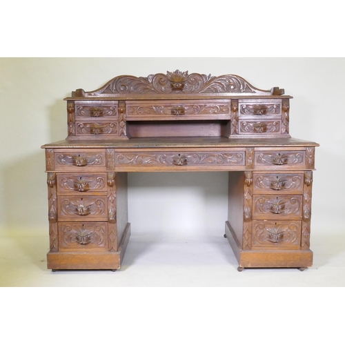 1067 - A Victorian oak nine drawer pedestal desk with mask carved handles, inset leather top and upper sect... 