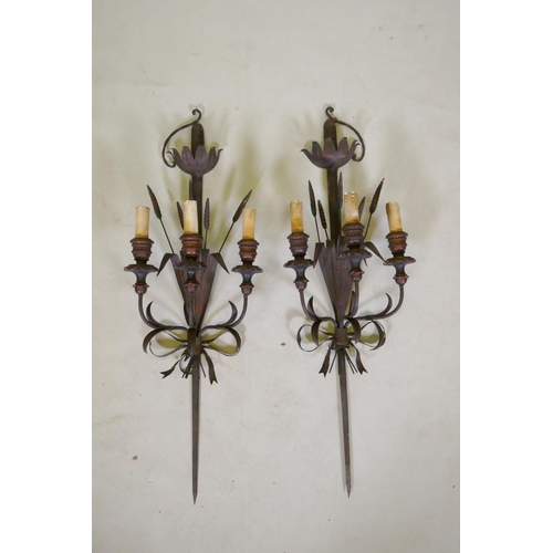 1081 - A pair of wrought iron and painted wood three branch sconces in the form of wheat ears and a sword h... 