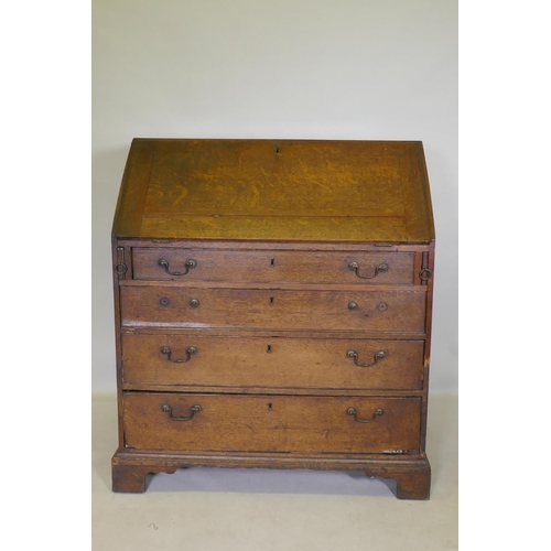 1118 - A Georgian oak fall front bureau with fitted interior over three drawers, raised on bracket supports