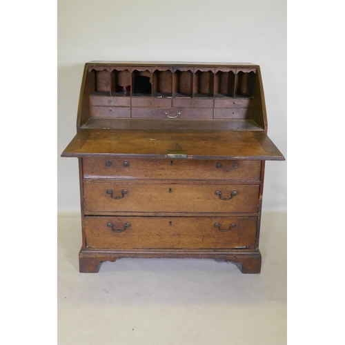 1118 - A Georgian oak fall front bureau with fitted interior over three drawers, raised on bracket supports