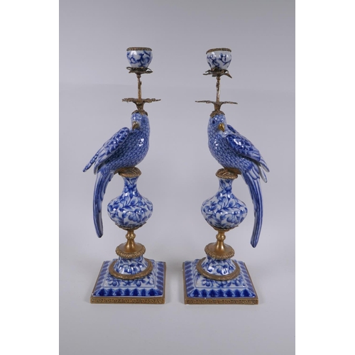139 - A pair of blue and white porcelain and gilt metal parrot candlesticks, 48cm high