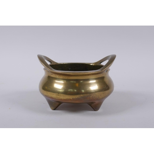 15 - An antique Chinese polished bronze censer with two phoenix eye handles and tripod supports, impress ... 