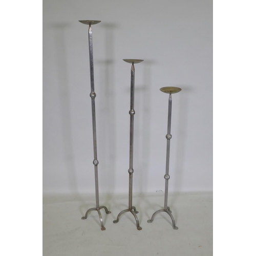 159 - Three graduated wrought metal pricket candlesticks, largest 113cm