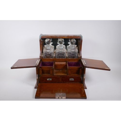 319 - A Victorian oak and silver plated three bottle tantalus, opening to reveal fitted compartments, the ... 