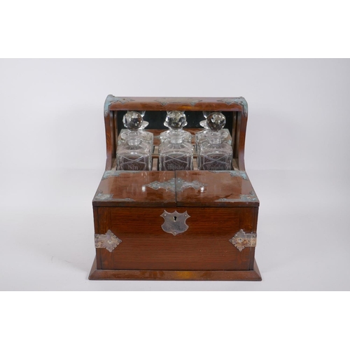 319 - A Victorian oak and silver plated three bottle tantalus, opening to reveal fitted compartments, the ... 