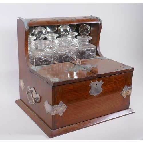 319 - A Victorian oak and silver plated three bottle tantalus, opening to reveal fitted compartments, the ... 