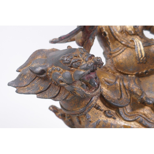 76 - A Sino Tibetan gilt bronze figure of a wrathful deity seated on a kylin, impressed double vajra mark... 