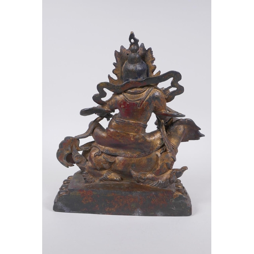 76 - A Sino Tibetan gilt bronze figure of a wrathful deity seated on a kylin, impressed double vajra mark... 