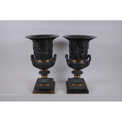 77 - A pair of Grand Tour style bronze two handled urns, with figural decoration and brass bands, mounted... 