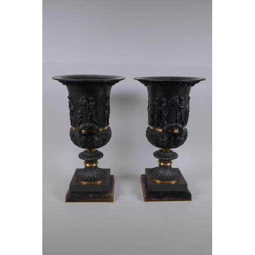 77 - A pair of Grand Tour style bronze two handled urns, with figural decoration and brass bands, mounted... 