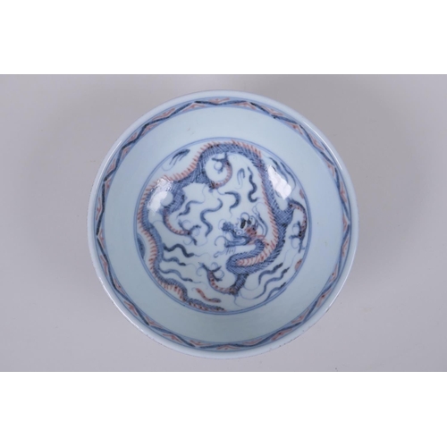 100 - A Chinese porcelain bowl with blue, white and red dragon decoration to the interior and a blue glaze... 