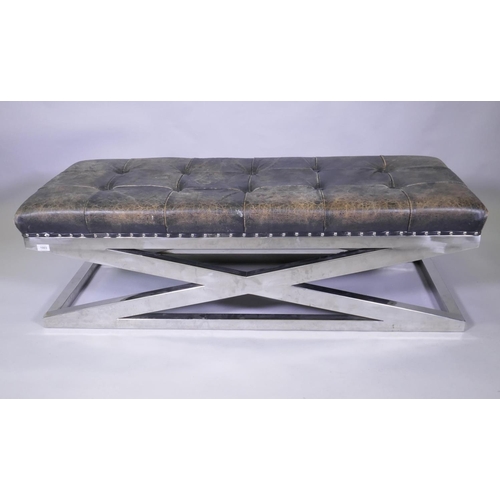 1003 - A buttoned leather bench raised on chromed metal supports, 150 x 55 x 45cm