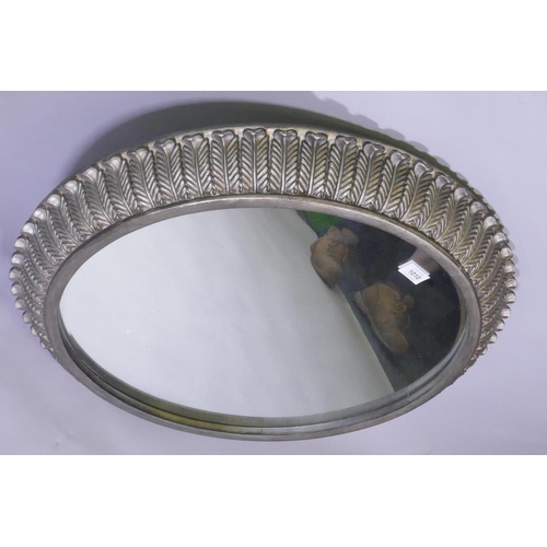 1010 - A contemporary metal leaf decorated cushion shaped wall mirror, 68cm diameter