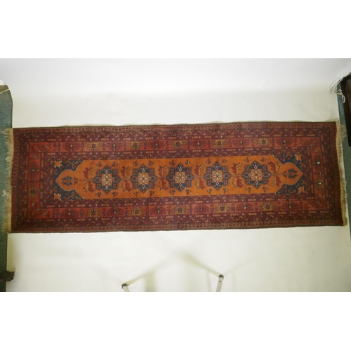 1016 - An antique oriental red ground wool runner decorated with geometric floral medallions and birds, 88 ... 