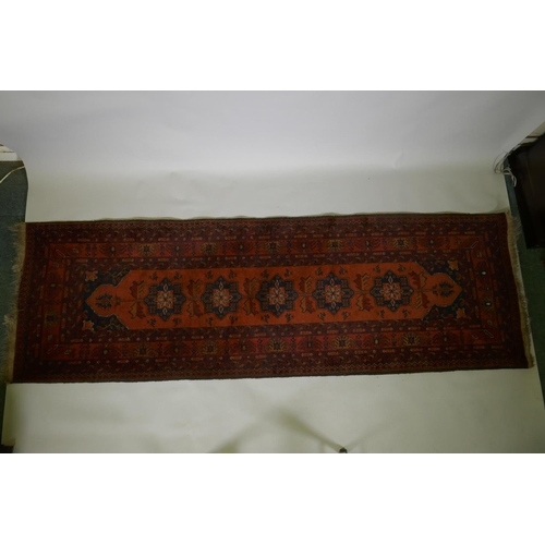 1016 - An antique oriental red ground wool runner decorated with geometric floral medallions and birds, 88 ... 