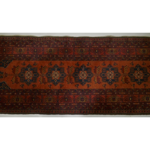 1016 - An antique oriental red ground wool runner decorated with geometric floral medallions and birds, 88 ... 