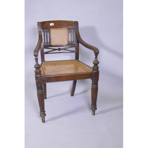 1021 - A C19th Anglo Indian style/Zanzibar hardwood elbow chair, with caned seat and back, reeded arms, rai... 