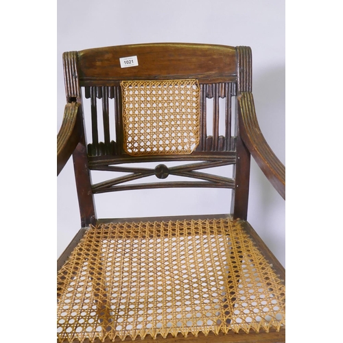 1021 - A C19th Anglo Indian style/Zanzibar hardwood elbow chair, with caned seat and back, reeded arms, rai... 